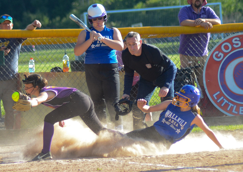 Wallkill Area’s Ava O’Flaherty slides safely into home plate as Pine Bush-Monticello pitcher Avery Ogden covers and takes the throw during Wednesday’s District 19 Majors softball tournament game at Goshen Little League.